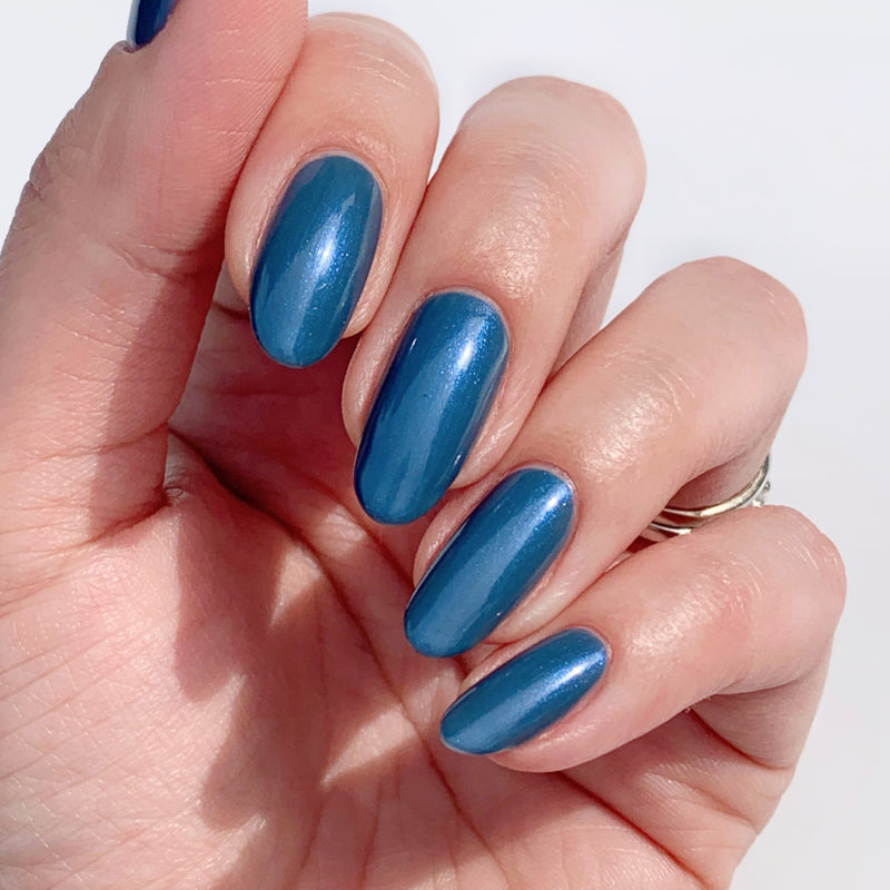 A hand with long nails painted in LONDONTOWN's Blue Diamond, held against a light background.