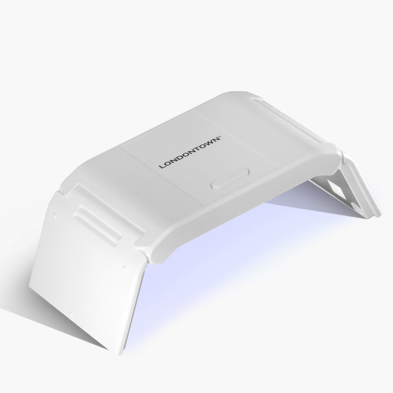 The LONDONTOWN Foldable UV/LED Gel Lamp is shown switched on, emitting blue light—an ideal compact device to quickly cure your nails and achieve flawless results anywhere.