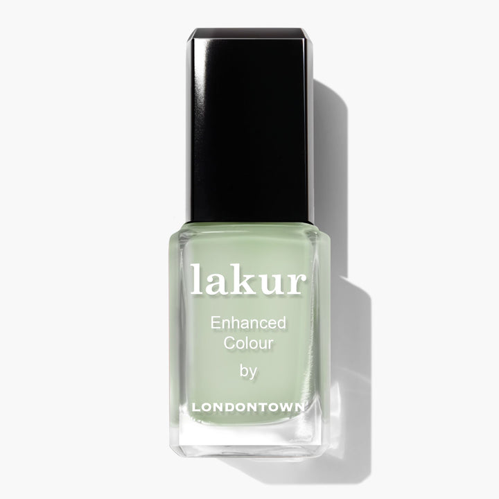 A bottle of Lichen enhanced color nail polish by LONDONTOWN in a light green shade, reminiscent of white sage, with a black cap.