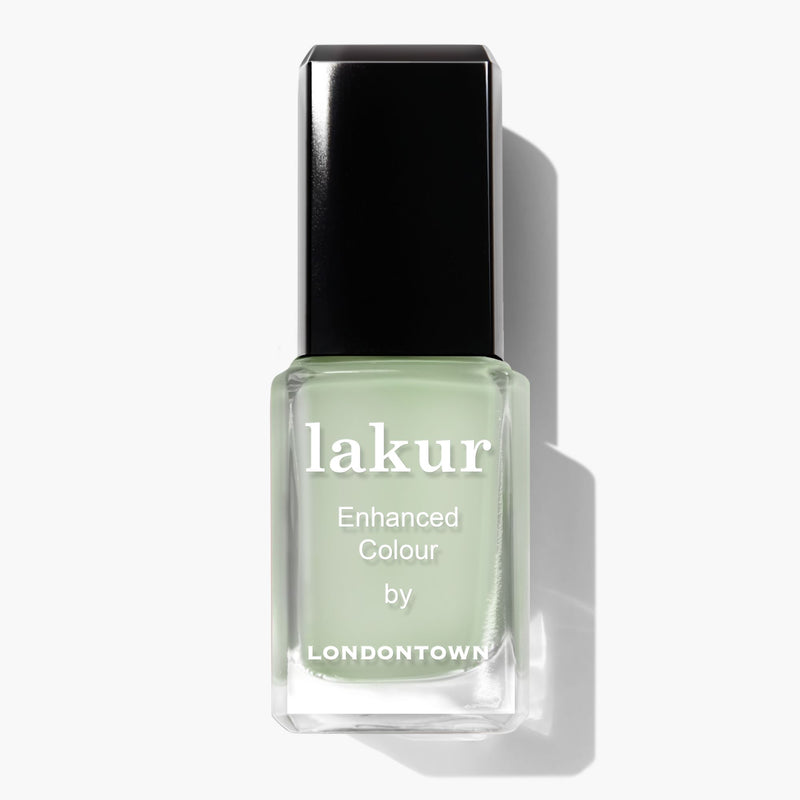 A bottle of Lichen enhanced color nail polish by LONDONTOWN in a light green shade, reminiscent of white sage, with a black cap.