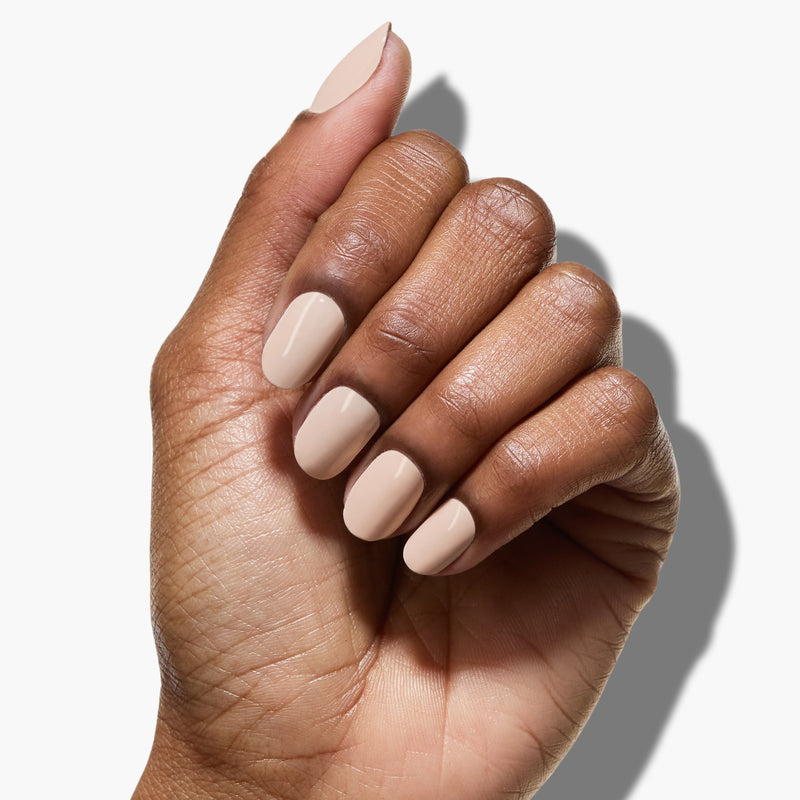 A hand with medium skin tone showcasing manicured nails painted in "Linen" by LONDONTOWN, a breezy light beige color, against a white background.