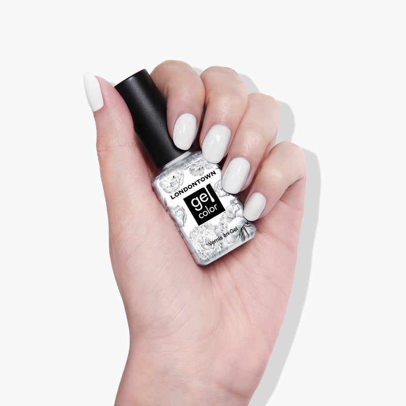 A hand with crisp white nail polish holds a bottle of LONDONTOWN's London Fog Gel Color nail polish against a cool, cloud-like background.