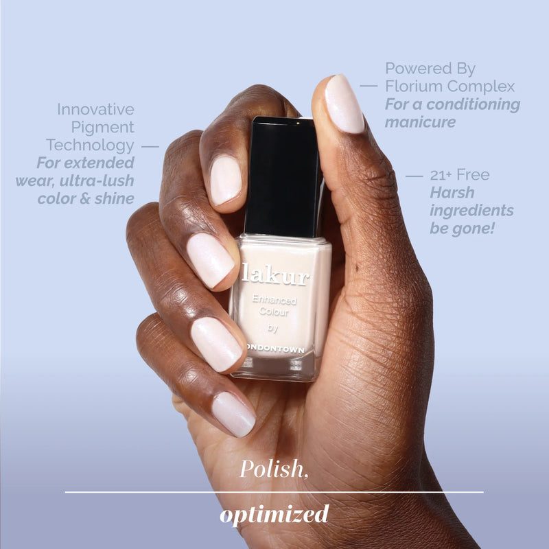 A hand with neatly manicured, pale pink nails holds a bottle of LONDONTOWN Milk Bath nail polish against a light purple background with product benefit text.