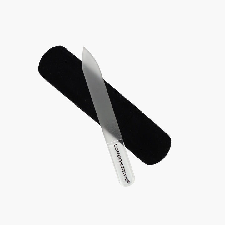 The Mini Glass Nail File - Clear by LONDONTOWN, featuring a white handle inscribed with "LONDONTOWN" and accompanied by a black fabric case, provides effortless, damage-free nail filing against a white background.