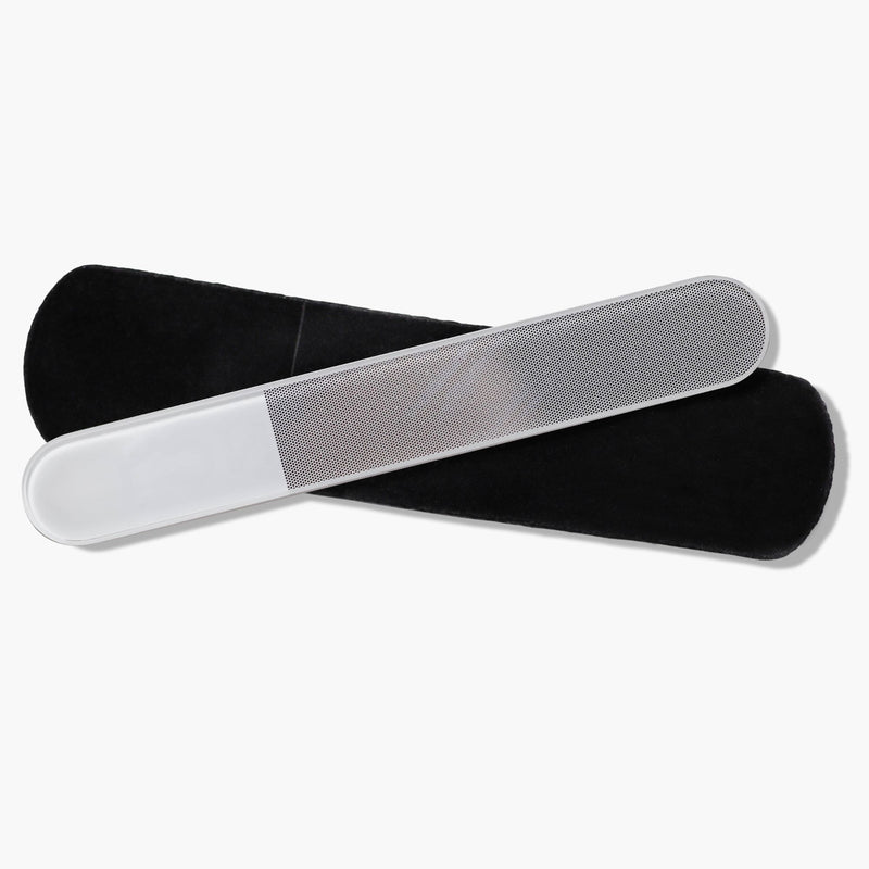 The Glass Nail Buffer by LONDONTOWN, featuring a frosted handle and textured surface, rests on a black pouch, ready to polish your nails to a smooth shine.