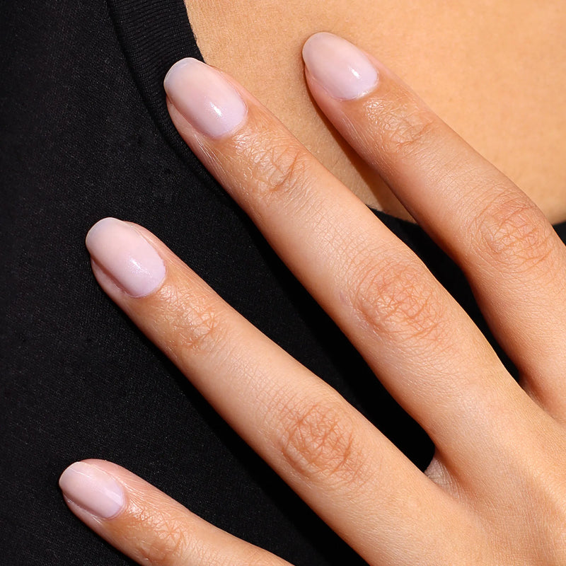 A close-up of a hand with neatly manicured, natural-looking nails on black fabric showcases the healthy look achieved using LONDONTOWN Original Illuminating Nail Concealer—perfect for anyone wanting to brighten dull nails.