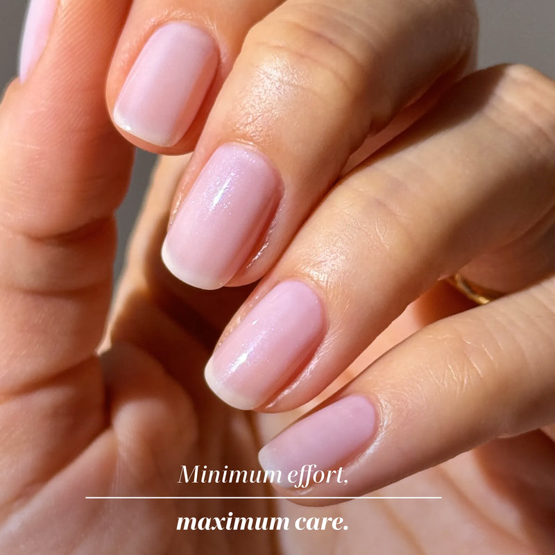 A close-up of a hand with short, neatly manicured nails painted in a light pink shade. Text: “LONDONTOWN Original Illuminating Nail Concealer: Minimum effort. Maximum care—even for dull nails.”.
