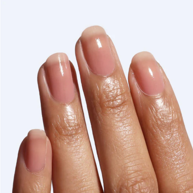 A close-up of three fingers with neatly filed, natural nails coated in LONDONTOWN’s Perfecting Nail Veil #4—a glossy nude shade with a hint of color—set against a light background, showcasing well-groomed nails.