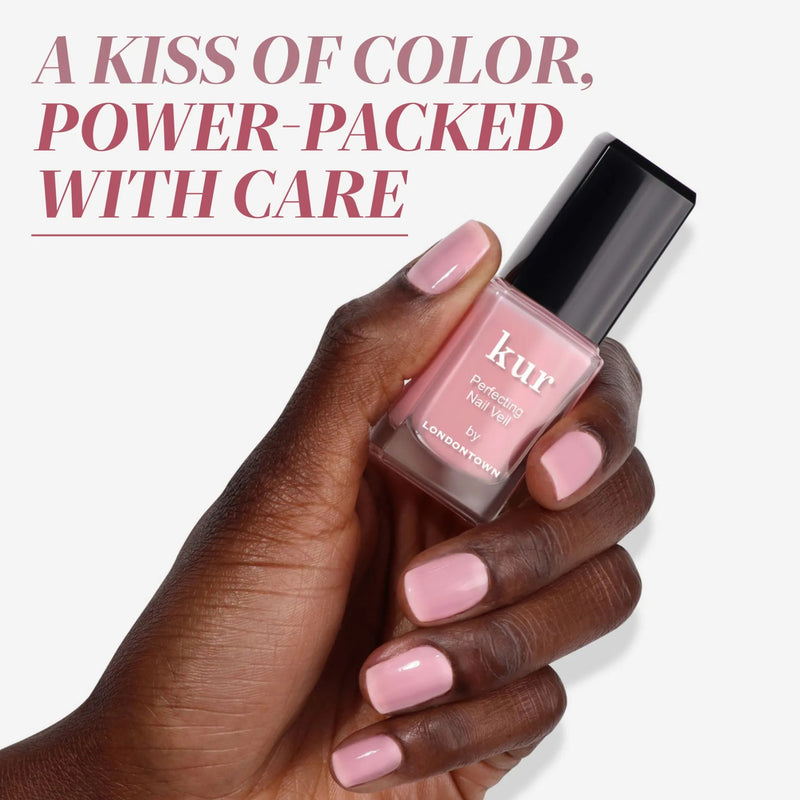 A hand with neatly manicured, light pink nails holds a bottle of LONDONTOWN Perfecting Nail Veil #7. Text above reads: "A kiss of color, power-packed with care—like your favorite moisturizing tinted lip balm.