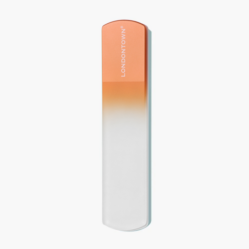 The Glass Foot File - Paloma by LONDONTOWN is a rectangular object with an orange top and white body, featuring the text "LONDONTOWN" on the top section, set against a plain white background. This product promises a gentle and smoothing experience with its effective formula.