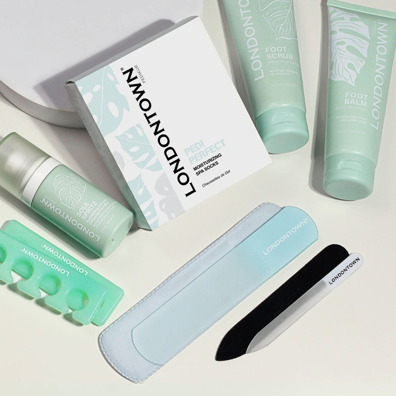 LONDONTOWN Pedi Discovery Set, featuring foot care essentials such as foot scrub, foot balm, nail buffer, nail clipper, toe separators, and a foot file neatly arranged on a white surface.