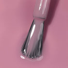Close-up of the LONDONTOWN Perfecting Nail Veil #11 brush applying clear polish on a pink surface, evoking the soft hues often seen in tinted lip balm and nourishing lip care products.