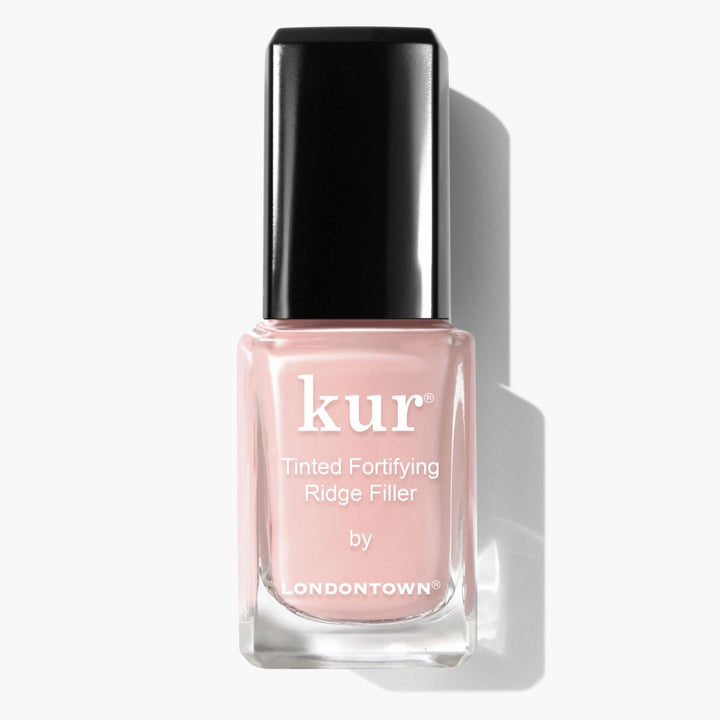 A LONDONTOWN Tinted Fortifying Ridge Filler - Petal Pink bottle offers a light pink tint and smooths nail ridges with ease, capped with a sleek black top.