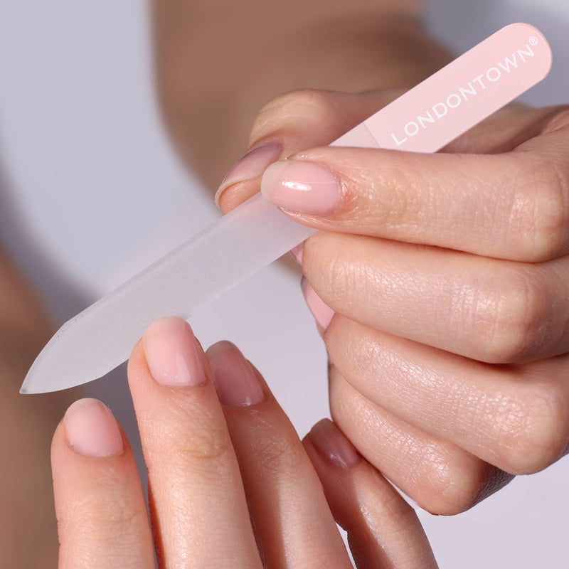 Close-up of a person effortlessly filing another person's nails with the Glass Nail File - Petal from LONDONTOWN. Both individuals have manicured nails in a neutral polish, ensuring damage-free results.