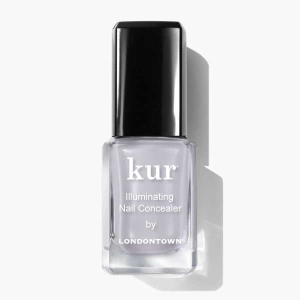 A bottle of LONDONTOWN Quartz Illuminating Nail Concealer, the instant nail perfector with a subtle soft gray glaze, featuring a sleek black cap on a white background.