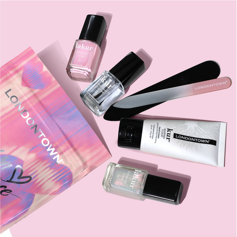 Flat lay of the LONDONTOWN Modern Chromance Valentine’s Day Set—featuring three nail polishes, a nail file, buffer, and hand cream—arranged on a soft pink background for a romantic touch.