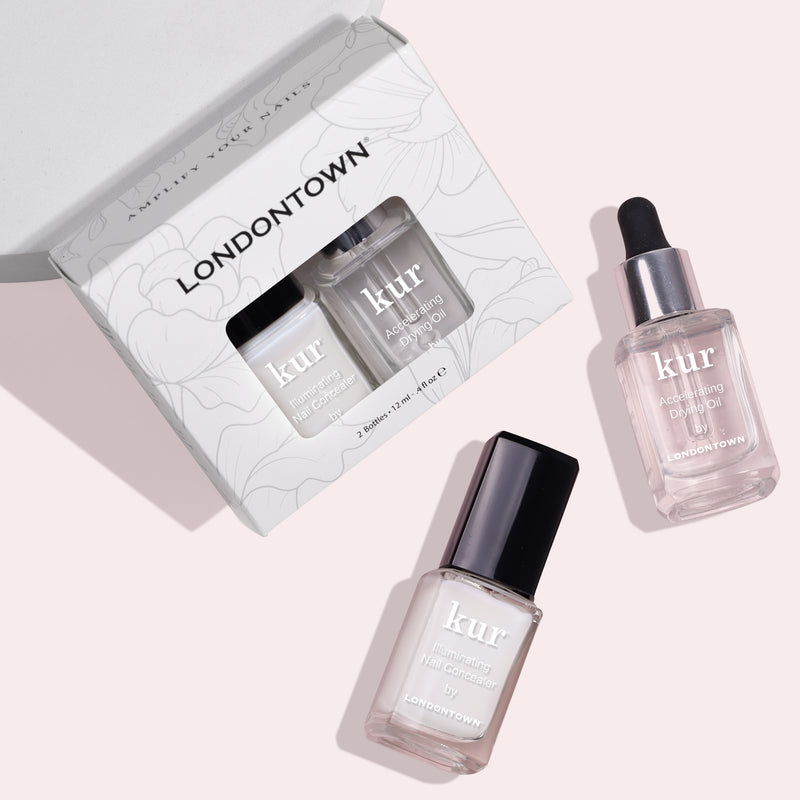 A LONDONTOWN Perfect in a Pinch nail care set featuring a boxed pair of nail products, one in a glass bottle with a black cap and another in a dropper bottle, ensuring polished perfection even in a pinch.