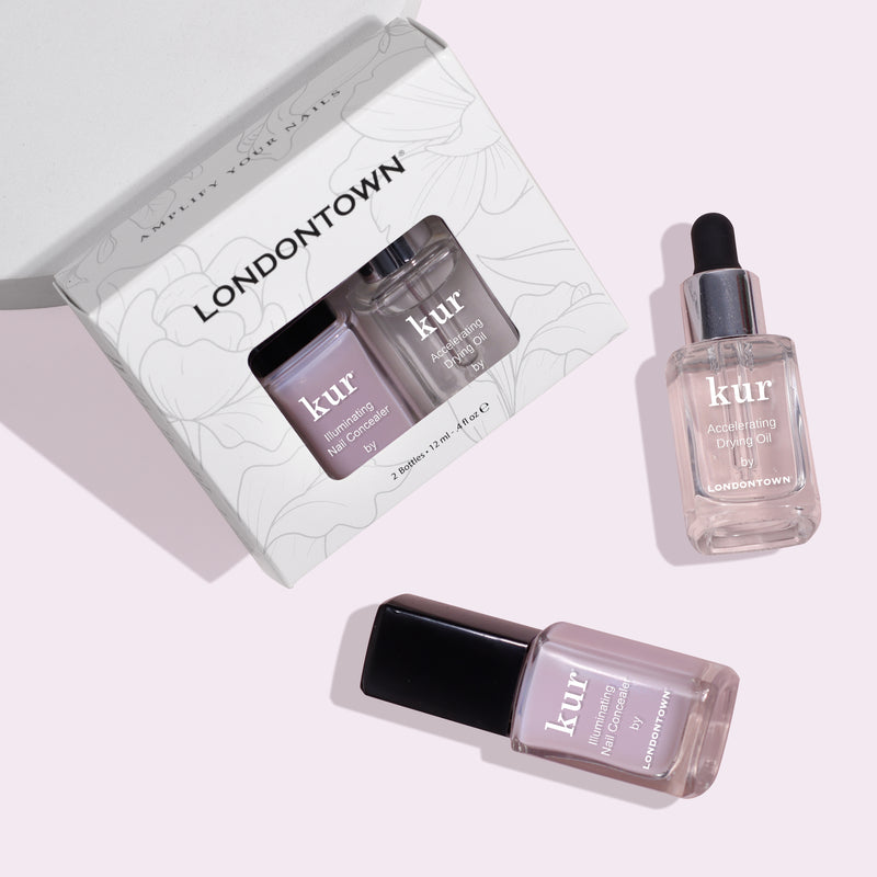 Three nail care products are displayed: an open box containing two bottles of Londontown's "Perfect in a Pinch: Pink" nail treatments, and one bottle of Londontown's "Perfect in a Pinch: Pink" Accelerating Drying Oil with a dropper for polished perfection.
