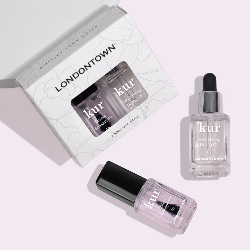 Introducing the S.O.S. Salon Staples from LONDONTOWN, a boxed set featuring a Strengthening Lacquer and Accelerating Drying Oil. Achieve a fast-drying manicure with salon secrets in each bottle, beautifully displayed beside the elegant box on a light surface.
