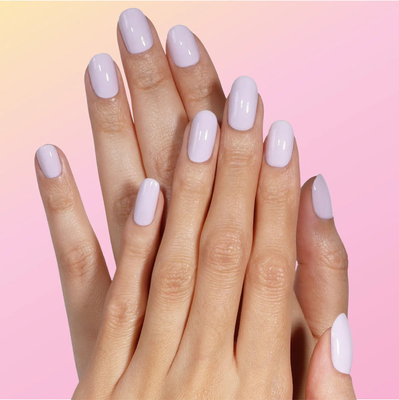 Close-up of hands with neatly manicured nails painted in LONDONTOWN’s Sweet Dreams, a glossy pale lavender shade, set against a soft gradient background.