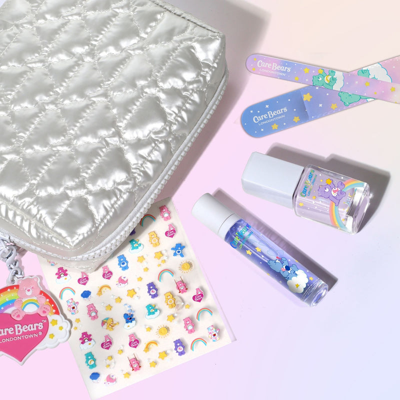 The Bear Necessities Set by LONDONTOWN, including a quilted silver pouch, two Care Bears nail files, nail polish, a roll-on bottle, and Care Bears stickers, is beautifully displayed on a pastel background.