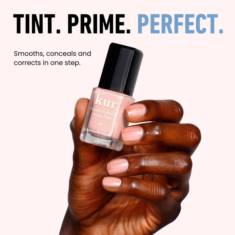 A hand holds LONDONTOWN's Tinted Fortifying Ridge Filler - Petal Pink against a light backdrop. The bold text reads "Tint. Prime. Perfect." Get smooth ridges and flawless nails every time with this hint of tint.