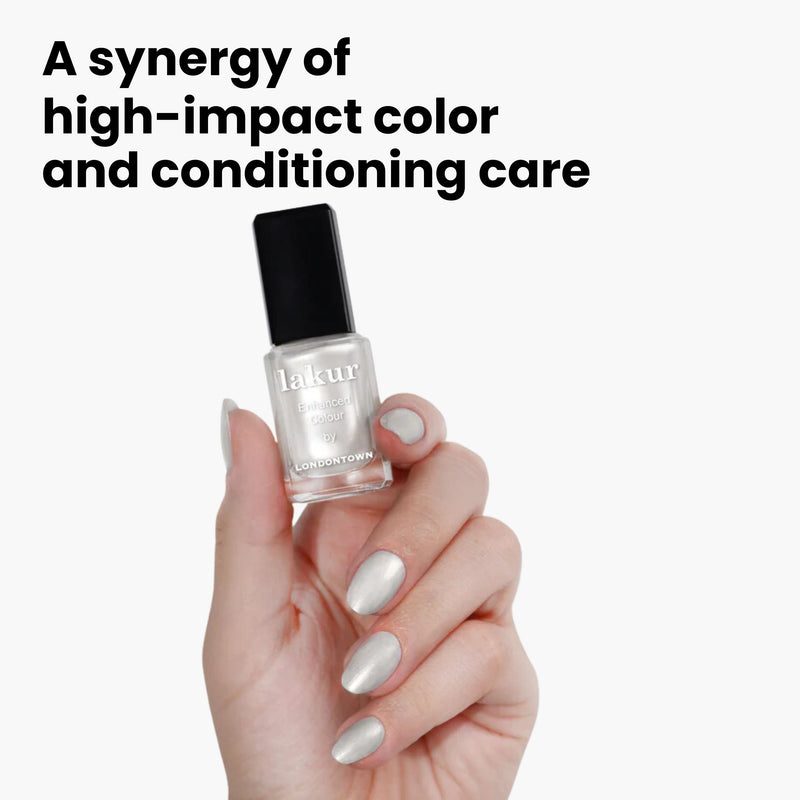 A hand with chrome-painted nails holds a bottle of LONDONTOWN's Lakur nail polish, "Powder," against a white background. Text reads, "A synergy of high-impact color and conditioning care.