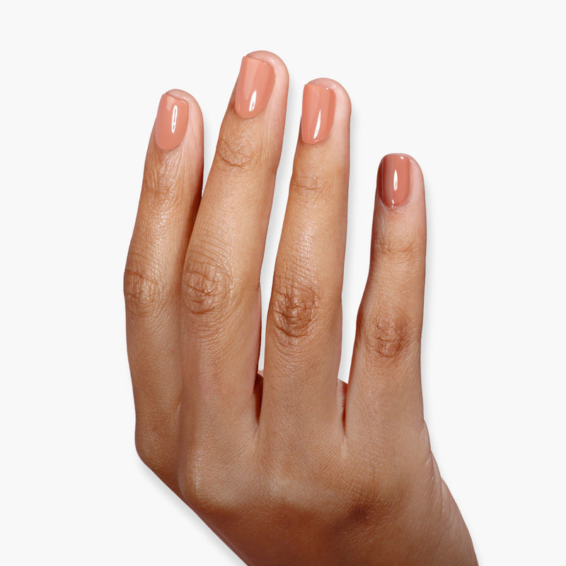 A hand with neatly manicured nails painted in LONDONTOWN's Pecan Pie, a glossy nude color reminiscent of tawny milk chocolate, is shown against a white background.