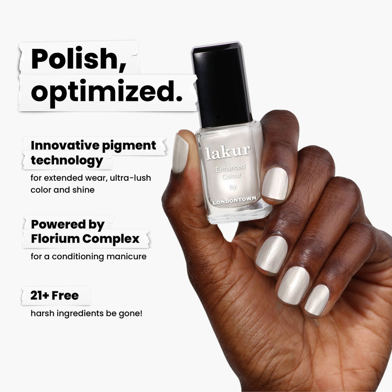 A hand elegantly holds a "Powder" nail polish bottle by LONDONTOWN, flaunting a creamy, powdered snow hue on the nails. It showcases innovative pigment technology and Florium Complex while being 21+ free from harsh ingredients.