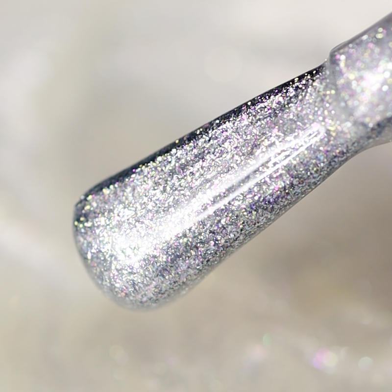 Close-up of LONDONTOWN's Shimmering Nail Highlighter - Mirror Ball, a brush coated with dazzling silver glitter set against a softly blurred light background.