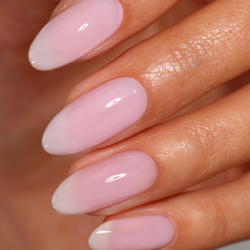 Close-up of a hand with neatly manicured fingernails painted in Magnolia Haze, a sheer petal pink shade from LONDONTOWN.