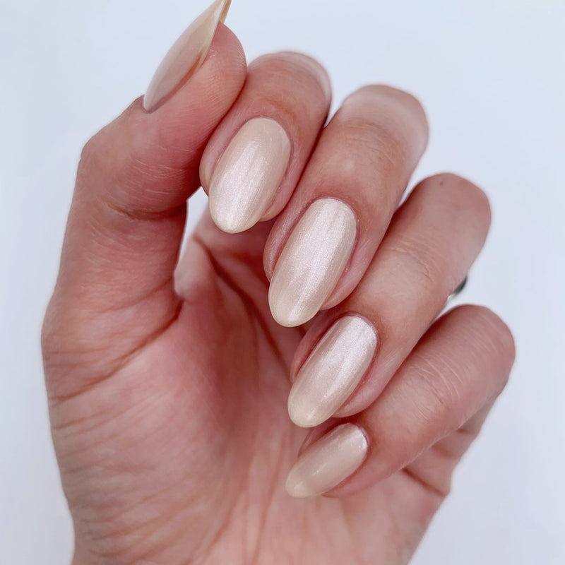A hand with almond-shaped, shimmering Pearl nude nails by LONDONTOWN against a soft, light background.
