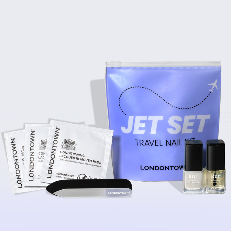 The LONDONTOWN Jet Set Travel Nail Kit includes mini lacquer remover pads, a nail file, and two travel-size polishes, all in a purple zip pouch—ideal for stylish nails on the go.