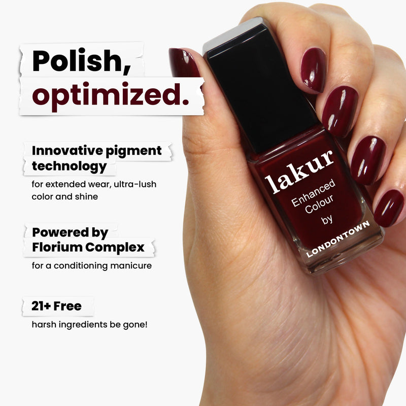 A hand holds a bottle of LONDONTOWN’s Elderberry nail polish, featuring innovative pigment technology and Florium Complex. The 21+ free formula adds depth and mystery with its blackened purple allure.