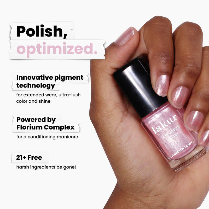 A hand holds a Pink Strawberry "lakur" nail polish by LONDONTOWN, showcasing innovative pigment and Florium Complex. This sweet shade with ultrafine glitter is free from 21+ harsh ingredients, providing a dazzling baby pink finish.