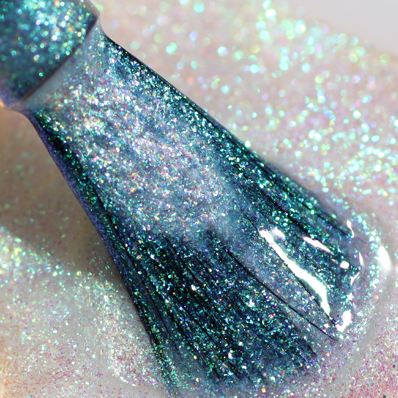 Close-up of the LONDONTOWN Shimmering Nail Highlighter - Stardust brush applying teal glitter polish to a sparkling white surface.