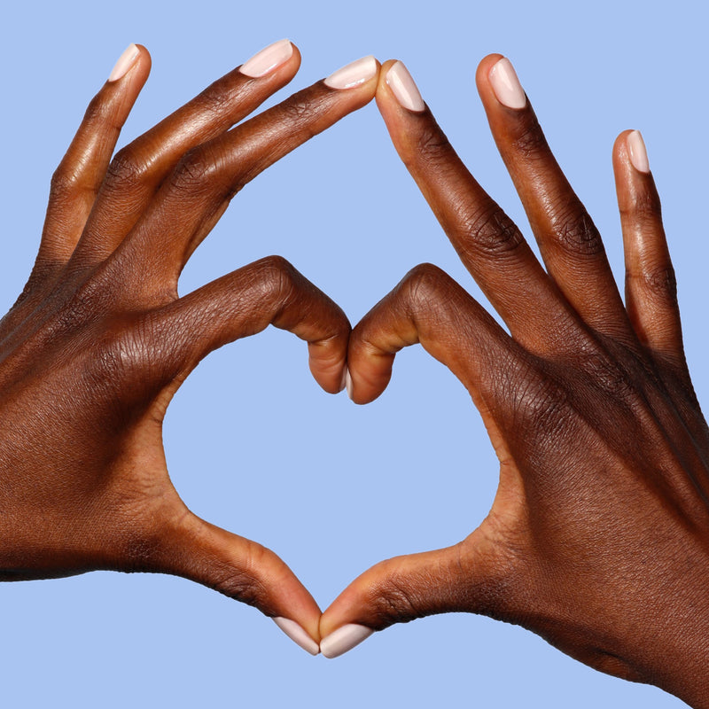 Two hands with creamy light pink nails, painted in LONDONTOWN's Double Scoop, form a heart shape against a light blue background.