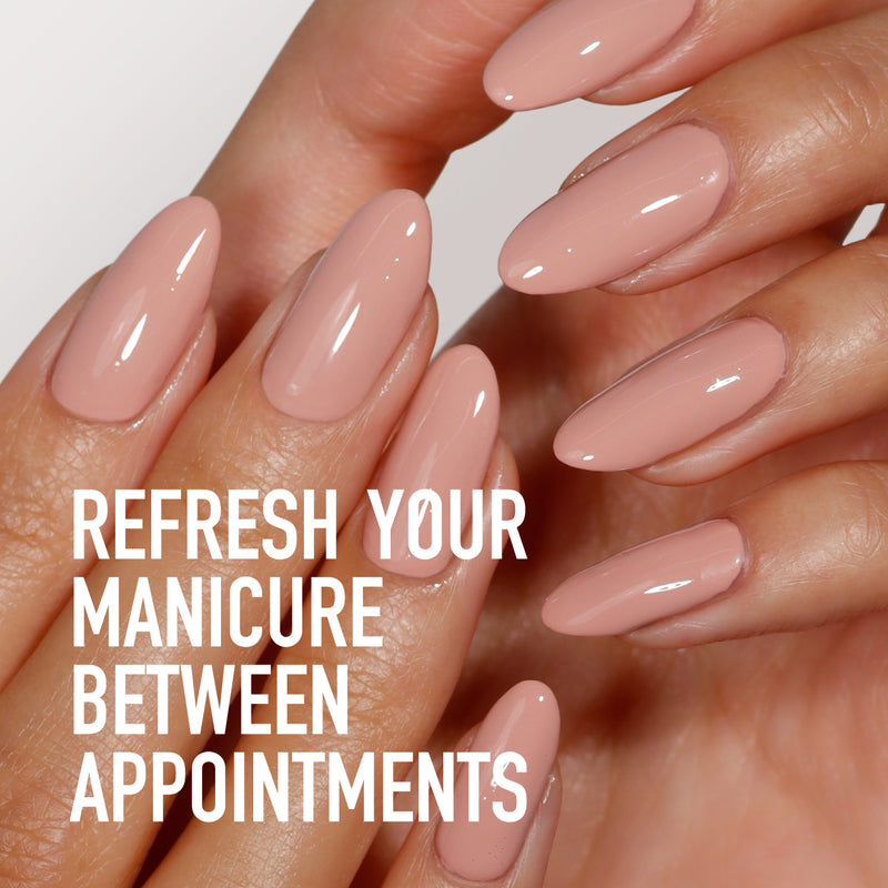 Close-up of a hand with long, glossy nude nails against a light background, accompanied by text: "Refresh your manicure between appointments with LONDONTOWN's Soft Touch Nail Scrub.