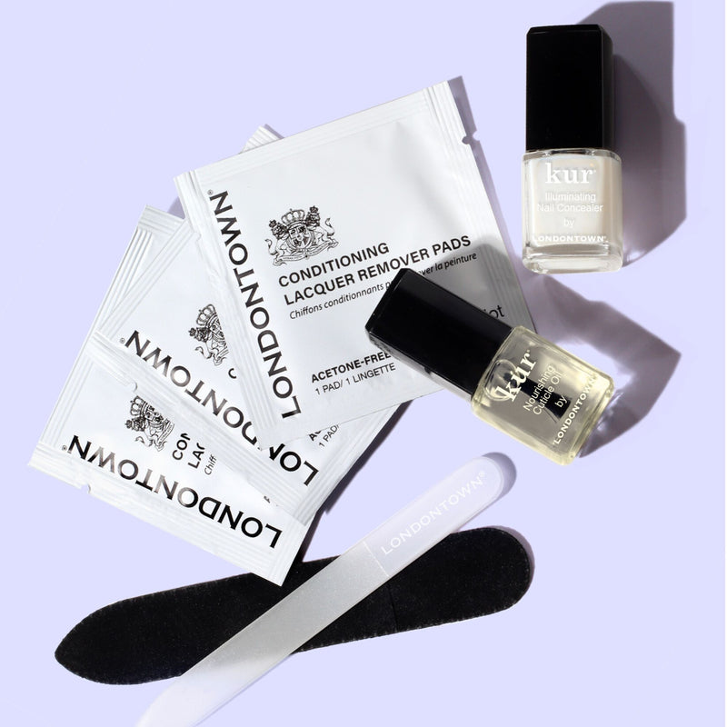 The LONDONTOWN Jet Set Travel Nail Kit features three lacquer remover pads, two polish minis, a black nail file, and a lavender buffer—perfect for manicures on the go—all shown on a light purple background.