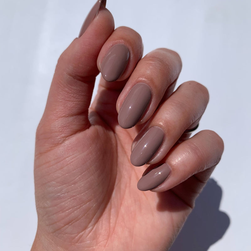 A hand with neatly manicured nails painted in LONDONTOWN's Chai, a spiced taupe crème, against a white background.