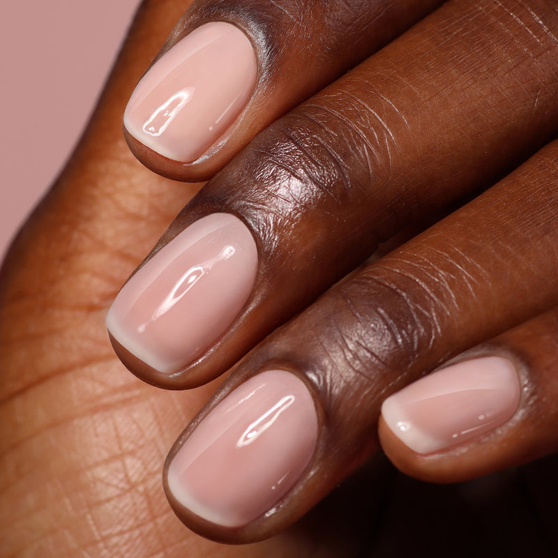 A close-up of a hand with neatly manicured nails painted in LONDONTOWN's Perfecting Nail Veil #4, a light pink glossy polish that highlights nail care and adds a subtle touch of color.