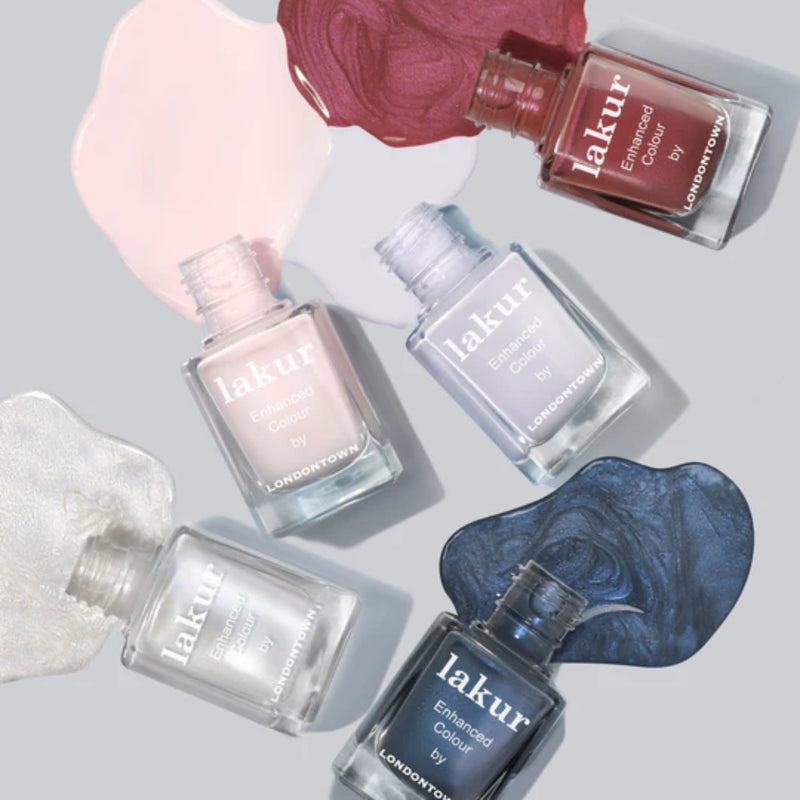 Five LONDONTOWN Lakur nail polish bottles in different shades, such as Slopeside’s delicate rose and a lustrous chrome, are elegantly displayed with their corresponding paint swatches.