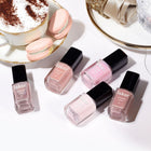 Five bottles of LONDONTOWN's Macaroon at Noon nail polish in light pink and taupe are displayed next to a foamy teacup with pastel macarons on a white surface.