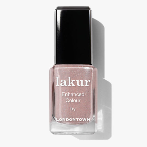 A nail polish bottle labeled "lakur Enhanced Colour by LONDONTOWN," showcasing the shade "Champagne in Bed," a neutral pink with a hint of sparkle.