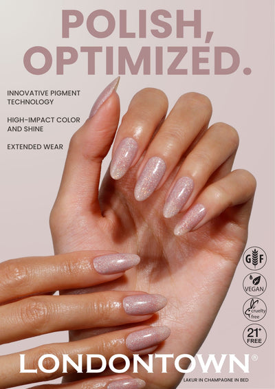 A hand with long, almond-shaped nails painted in shimmery pale pink polish is shown, with product claims and the LONDONTOWN brand featured in the background. Product: Londontown Poster #5.