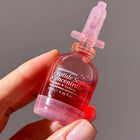 A hand holds a small pink bottle labeled “Peptide Serum Concentrate” by LONDONTOWN, a nourishing serum for nail and cuticle care, featuring a clear dropper top.