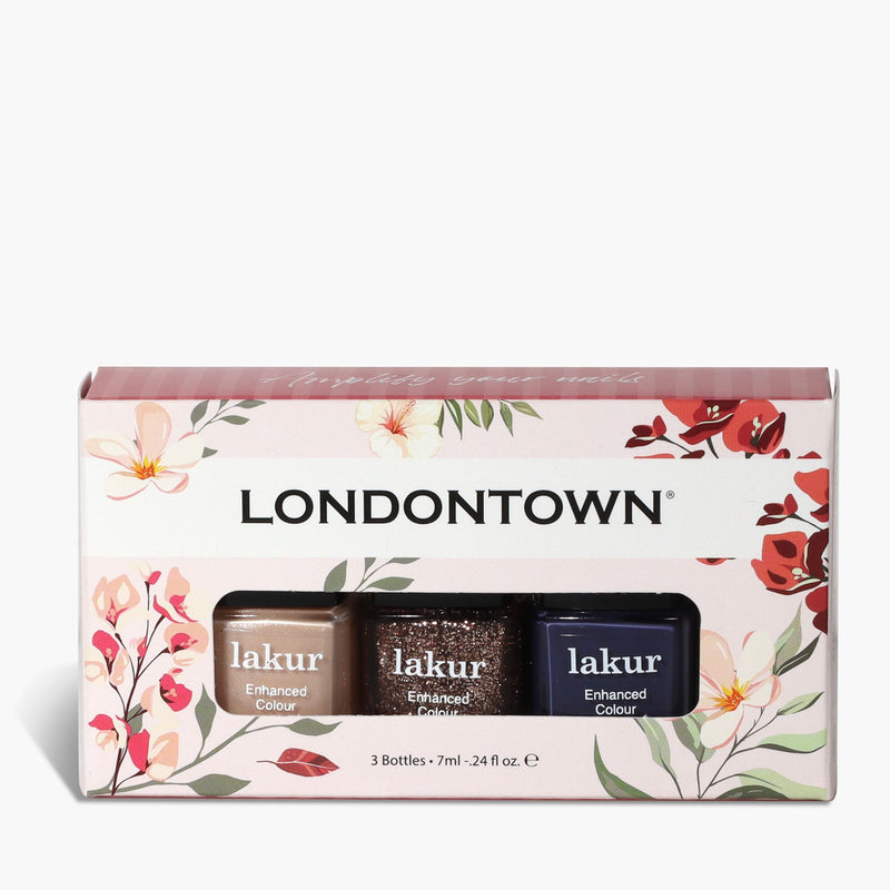 The LONDONTOWN Moonlit Botanica Mini lakur trio is a boxed set featuring three nail polishes—pink, glittery brown, and dark blue—packaged in a box adorned with floral designs.