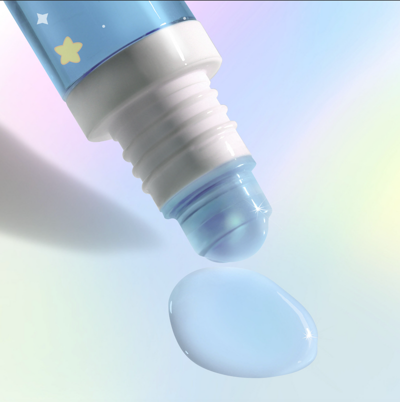 A close-up of LONDONTOWN's Roll & Glow Cuticle Oil - Cotton Candy Cloud, a pocket-sized rollerball bottle releasing a drop of blue liquid onto a pastel background.