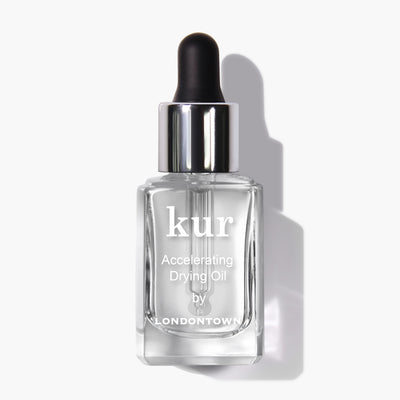 A pristine white background showcases a clear glass bottle with a black dropper cap, labeled "Accelerating Drying Oil by LONDONTOWN." This fast-drying manicure botanical oil blend is designed for optimal performance.