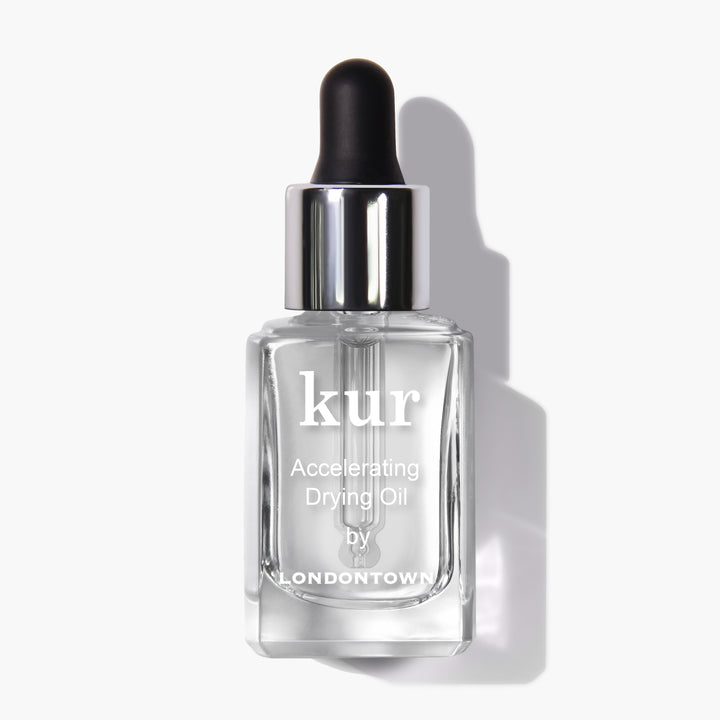 A pristine white background showcases a clear glass bottle with a black dropper cap, labeled "Accelerating Drying Oil by LONDONTOWN." This fast-drying manicure botanical oil blend is designed for optimal performance.
